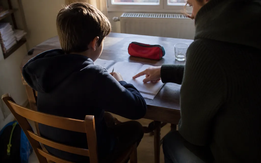 Enfant travaillant son anglais avec un adulte à la table d’un appartement lyonnais