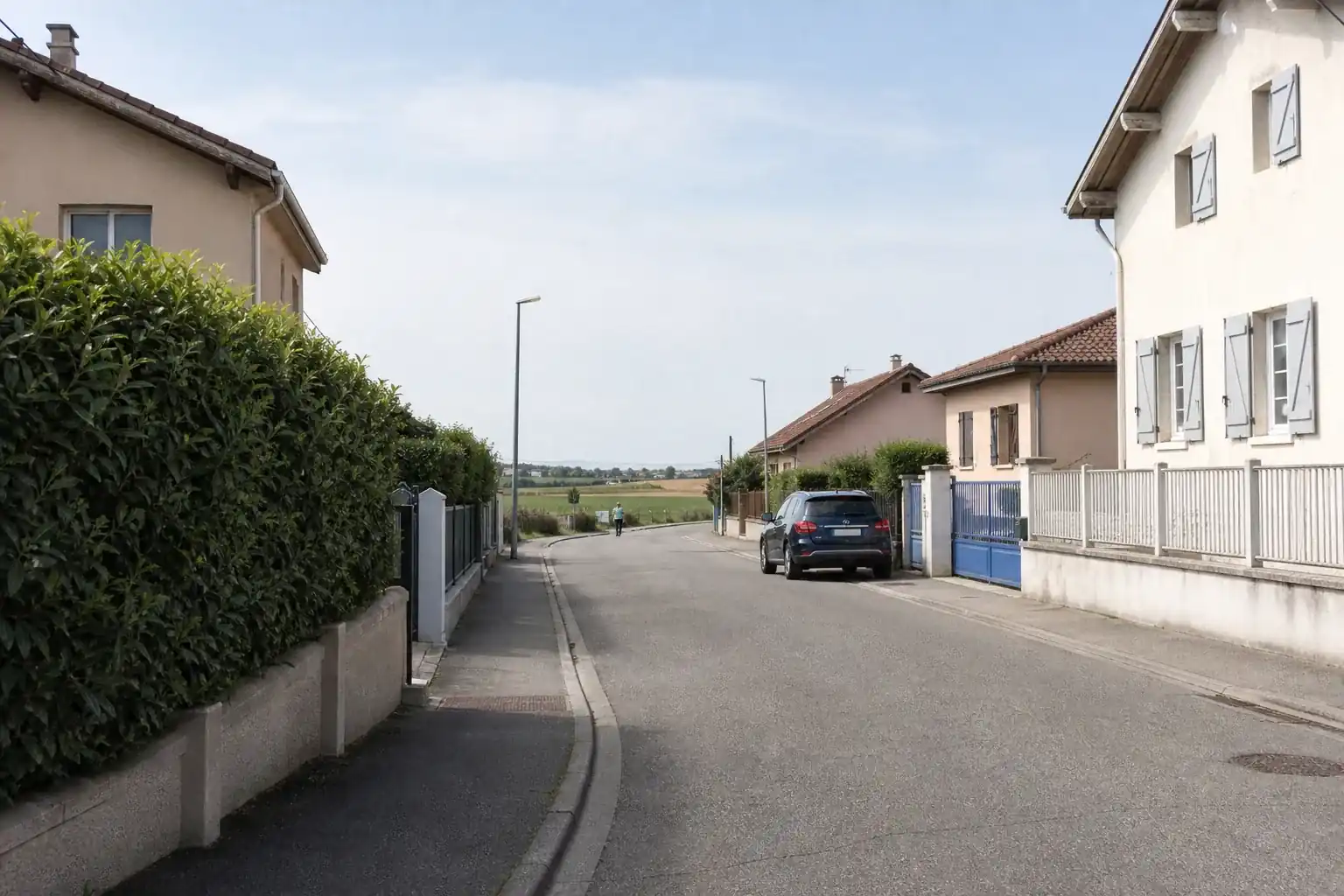 Rue tranquille de Charvieu-Chavagneux, maisons à volets et plaine ouverte