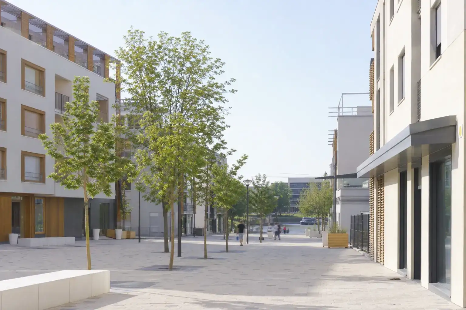 Place réaménagée de Vaulx-en-Velin, bâtiments bas récents et jeunes arbres