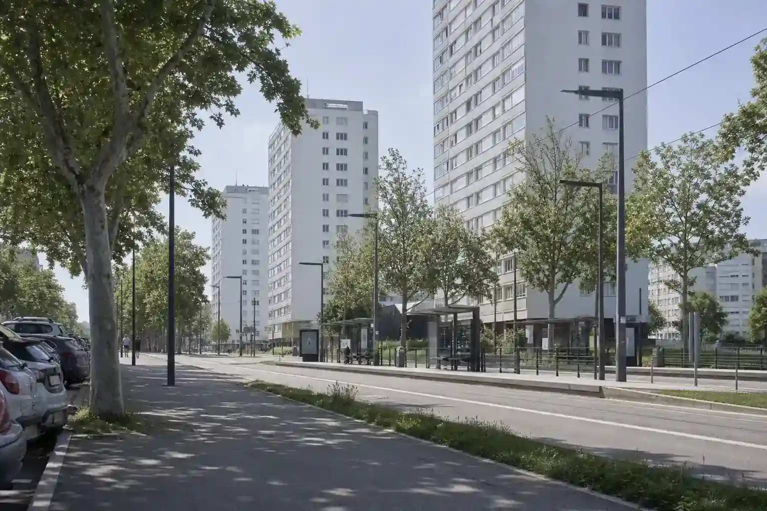 Boulevard de Vénissieux à midi, tours d’habitation claires et arrêt de tramway